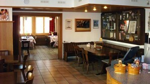 Ein Restaurant mit Holzvertäfelung, einer Bar und einem Essbereich mit Tischen und Stühlen.