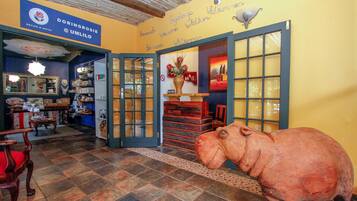 Un hall d’hôtel avec une grande sculpture d’éléphant en bois, un comptoir d’accueil et une enseigne bleue portant le nom « Doringrosie ».