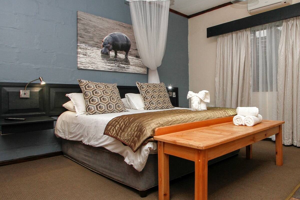 A bedroom with a bed, bedside table, and a large window with curtains.
