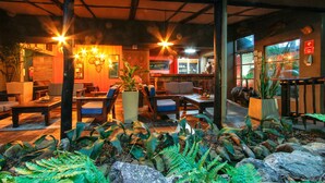 An indoor seating area with tables and chairs, surrounded by potted plants and rocks. - Umlilo Lodge (St. Lucia)