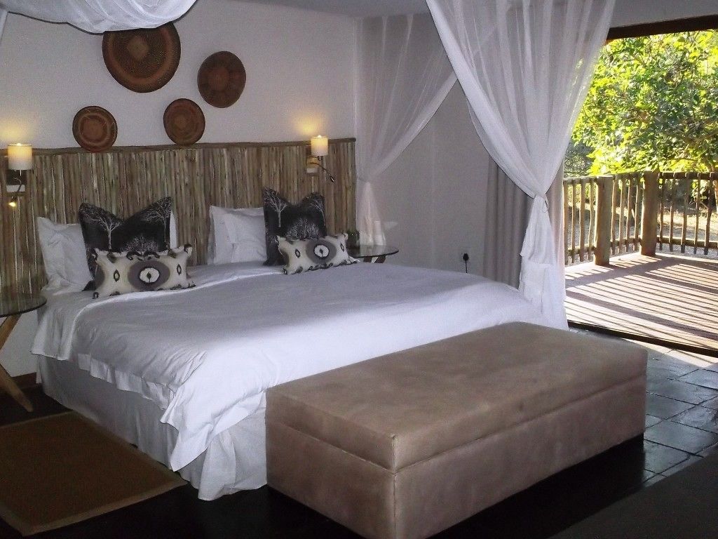 A bedroom with a large bed, a wooden headboard, and a view of the outdoors.