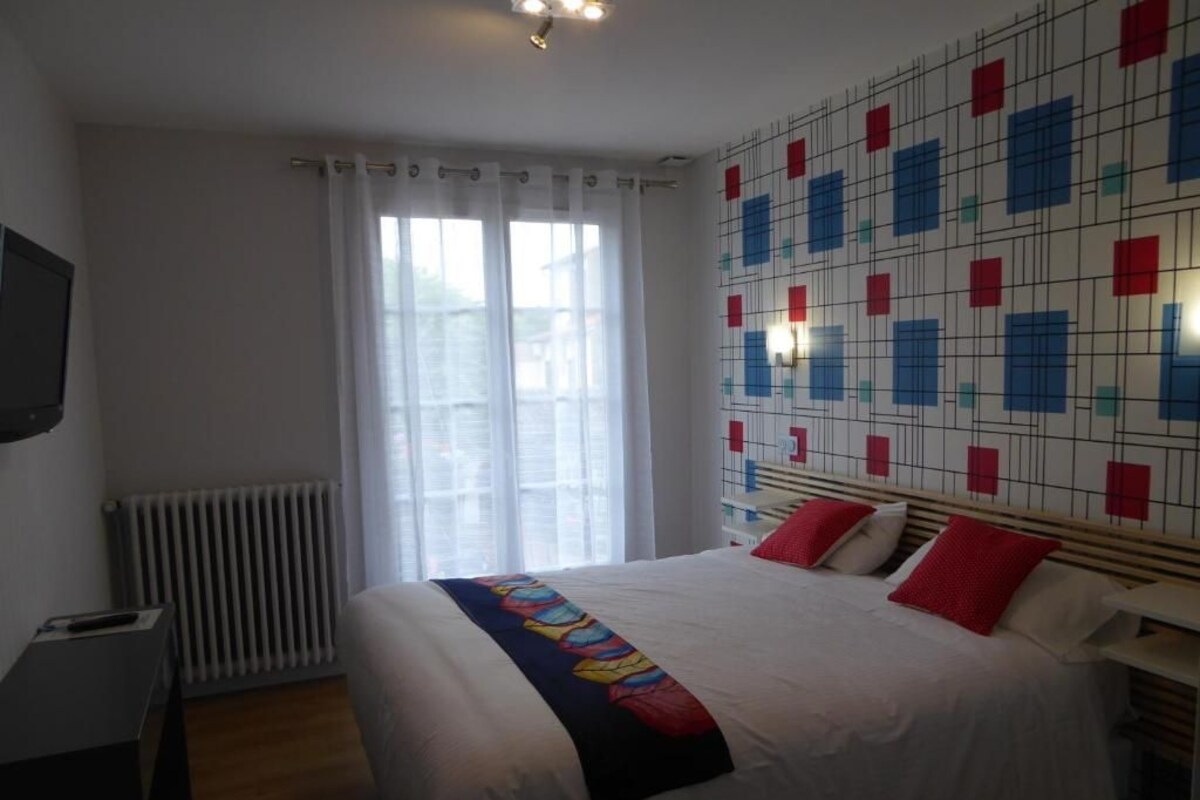 A hotel room with a bed, a TV, a radiator, and a patterned wall.