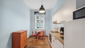 A compact kitchen with a dining table and chairs, a coffee maker, and a cabinet. - Pension 1A Apartment (Berlin)