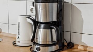 Una cafetera con pantalla digital y un hervidor de agua independiente sobre una encimera de cocina.