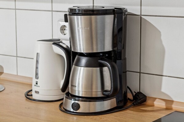 Una cafetera con pantalla digital y un hervidor de agua independiente sobre una encimera de cocina.