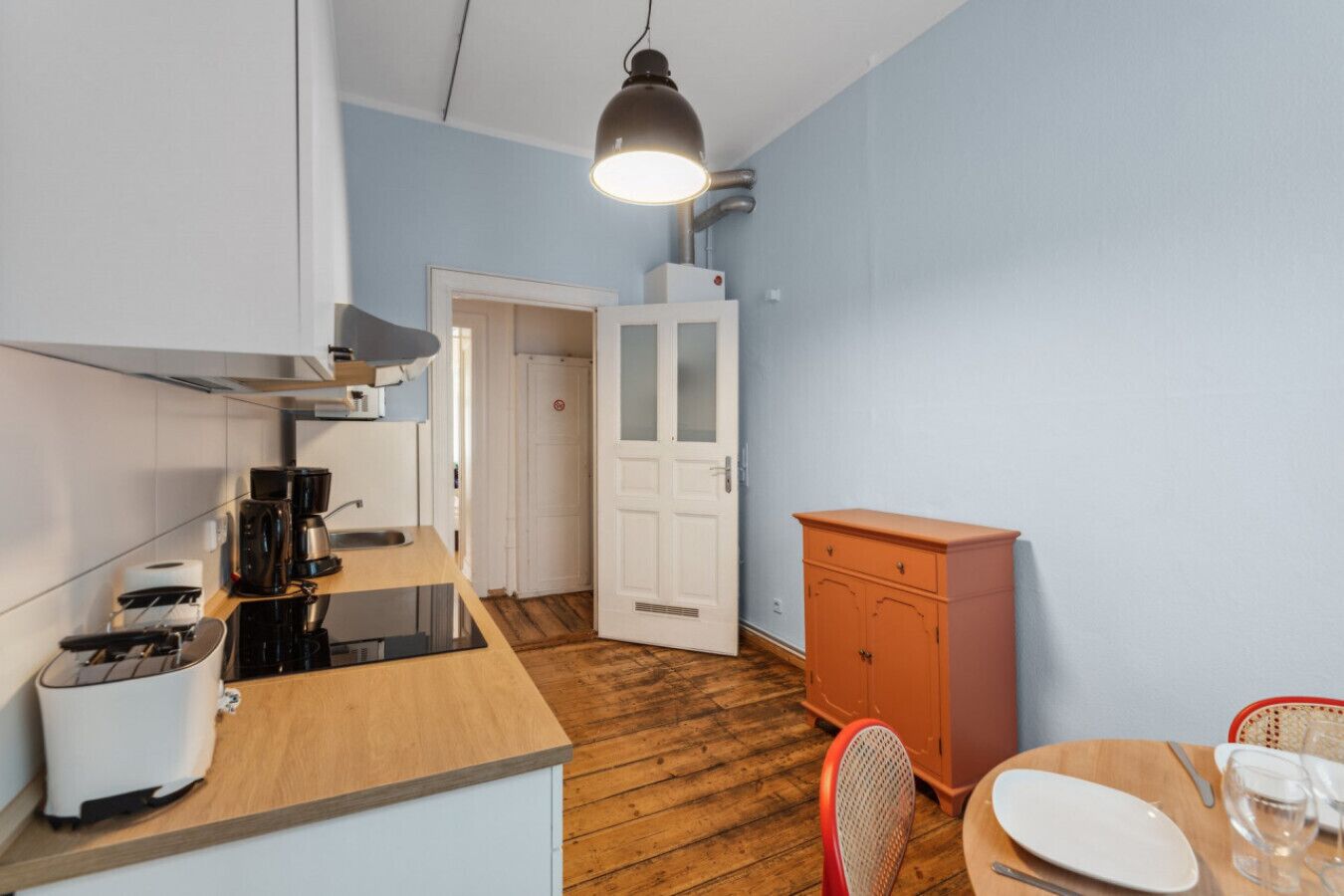 A compact kitchen with a coffee maker, toaster, and a wooden countertop.