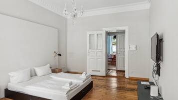 A modern bedroom with a large bed, a chandelier, and a TV mounted on the wall.