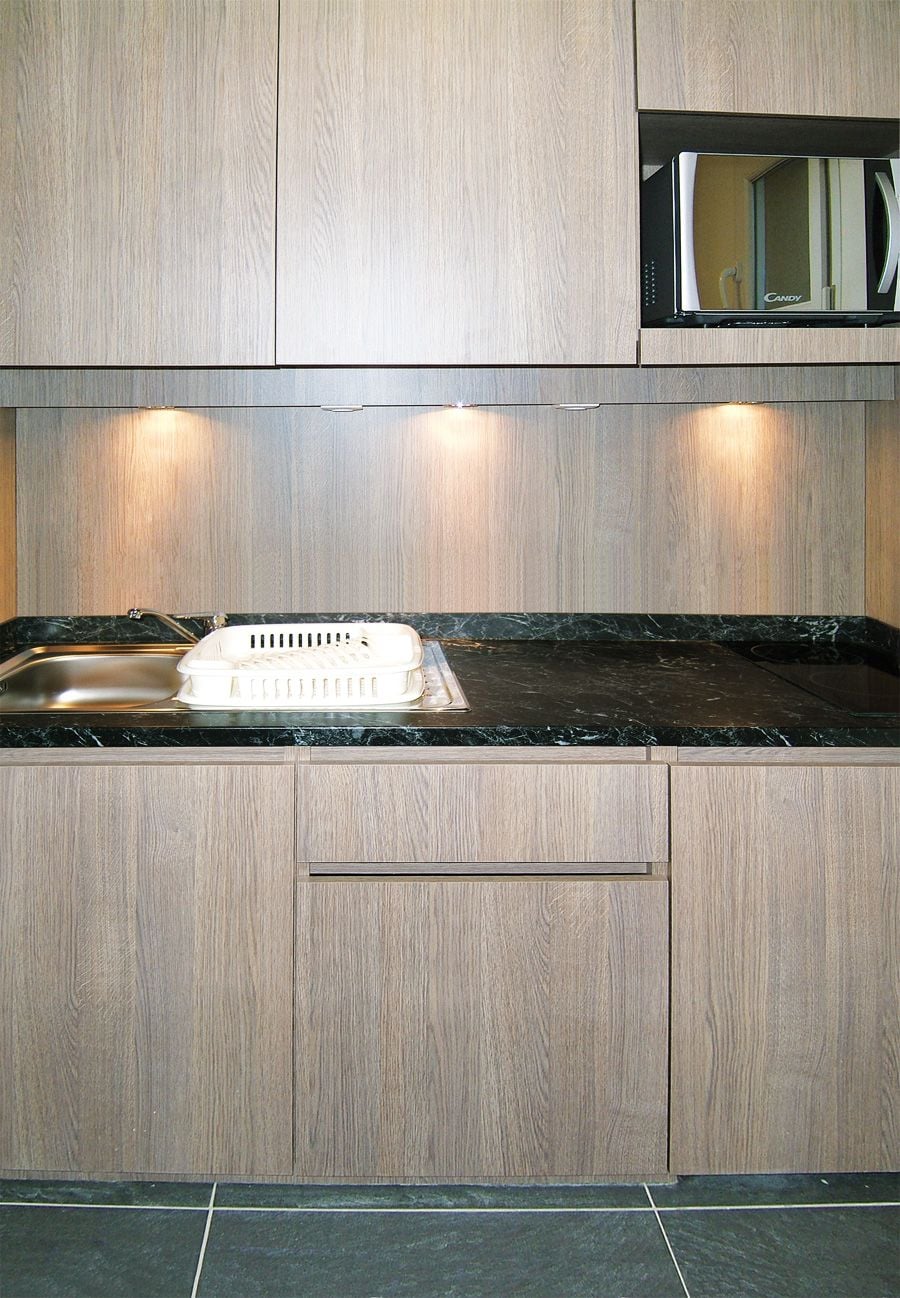 A kitchen with wooden cabinets, a black countertop, and a microwave.
