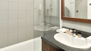 A modern bathroom with a glass-enclosed shower, a white sink, and a mirror above it. - Zenitude Hotel-residences Roissy Village (Roissy-en-France)