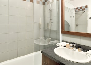 A modern bathroom with a glass-enclosed shower, a white sink, and a mirror above it.