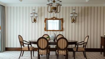 A dining room with a round table, six chairs, a chandelier, wall sconces, and a mirror.