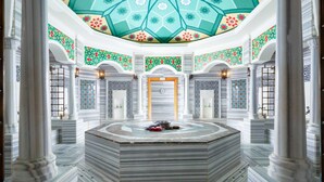 A spacious lobby with a central circular seating area, large columns, and a decorative ceiling. - Rixos Almaty (Almaty)