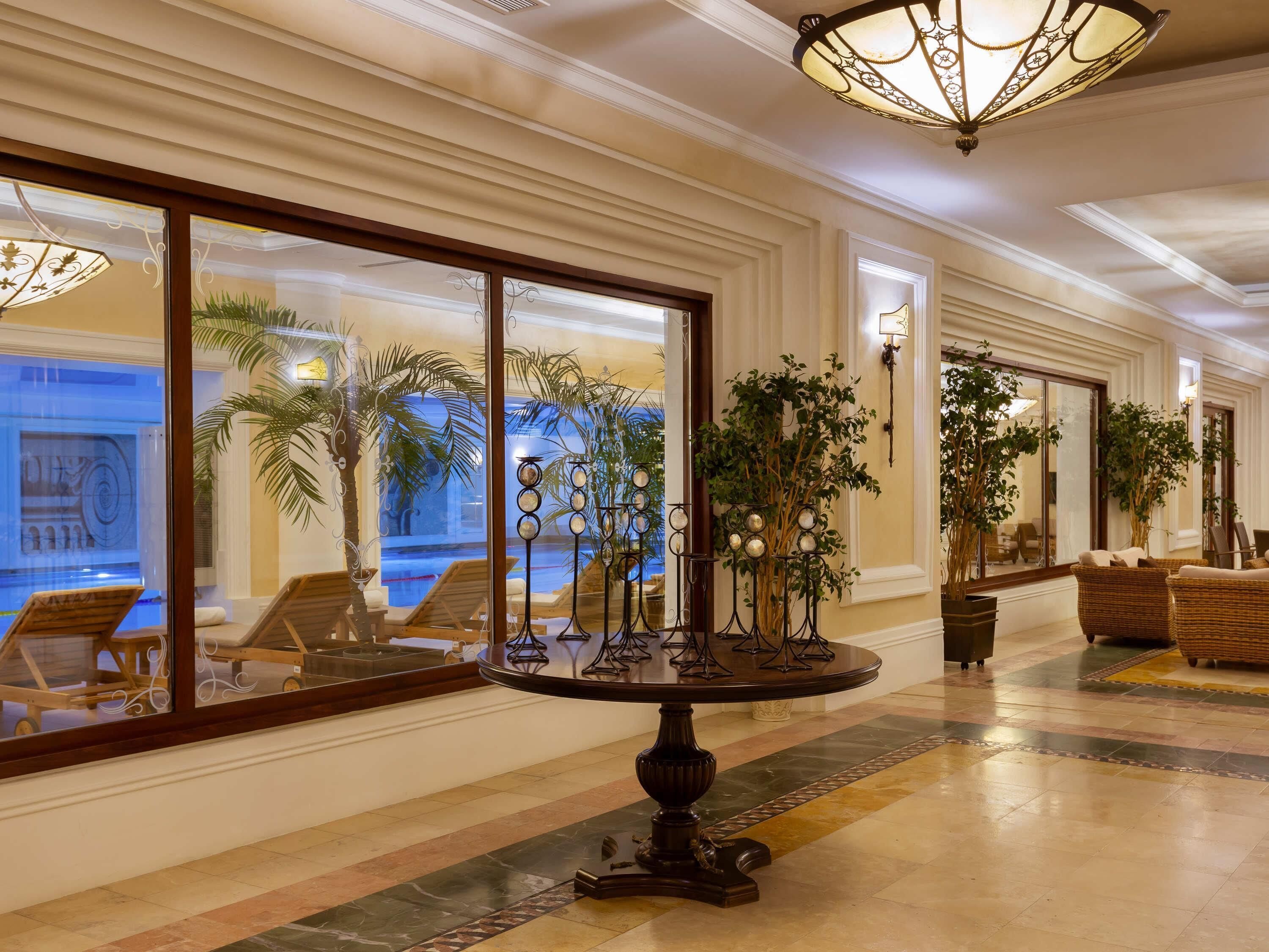 Un vestíbulo de hotel con vista a una piscina, una mesa redonda y muebles de mimbre.