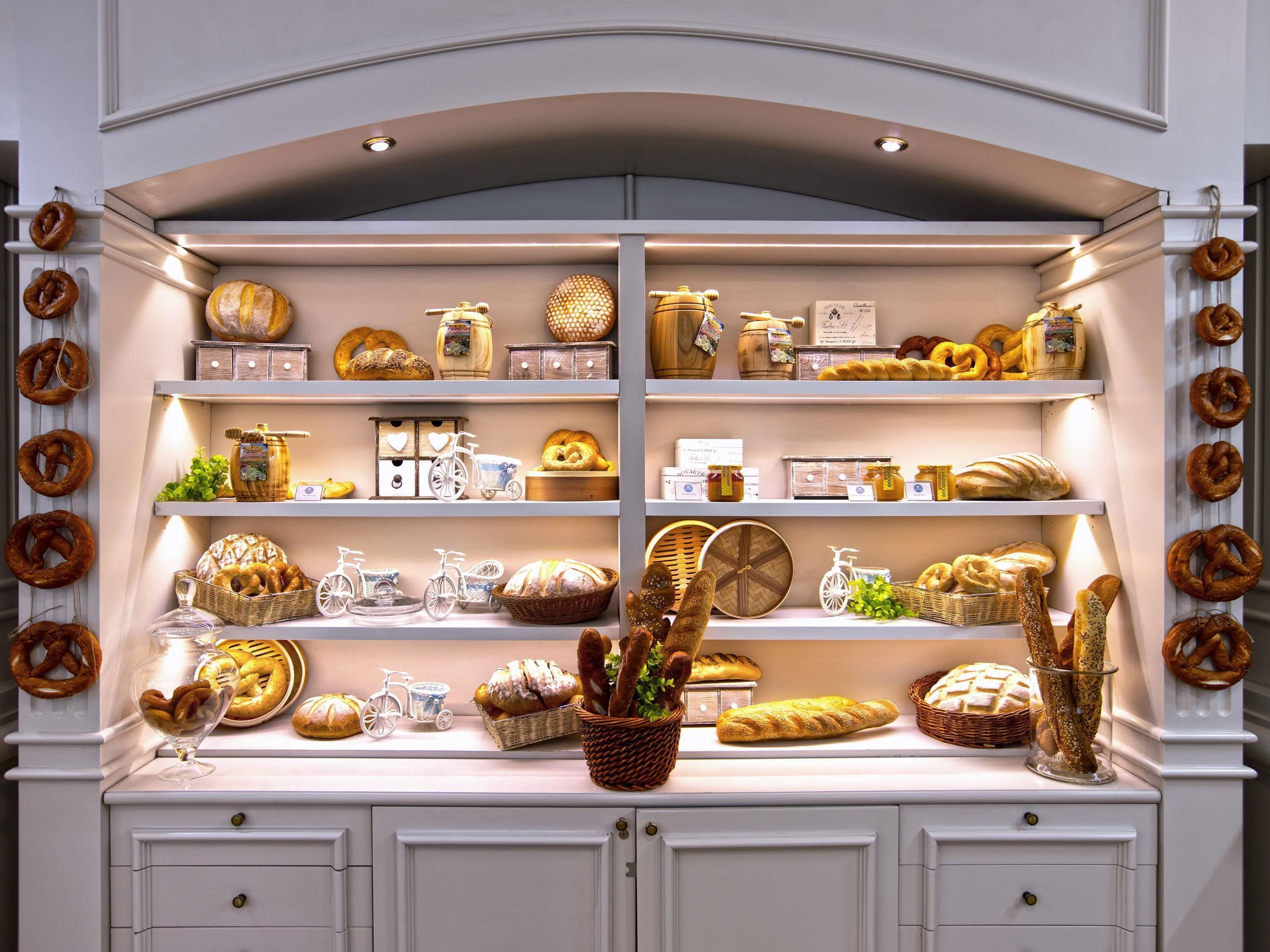 Una vitrina de panadería con diversos panes, pasteles y tarros de miel.