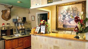 A reception desk with a framed floral painting, a deer head, and a sign about pets.