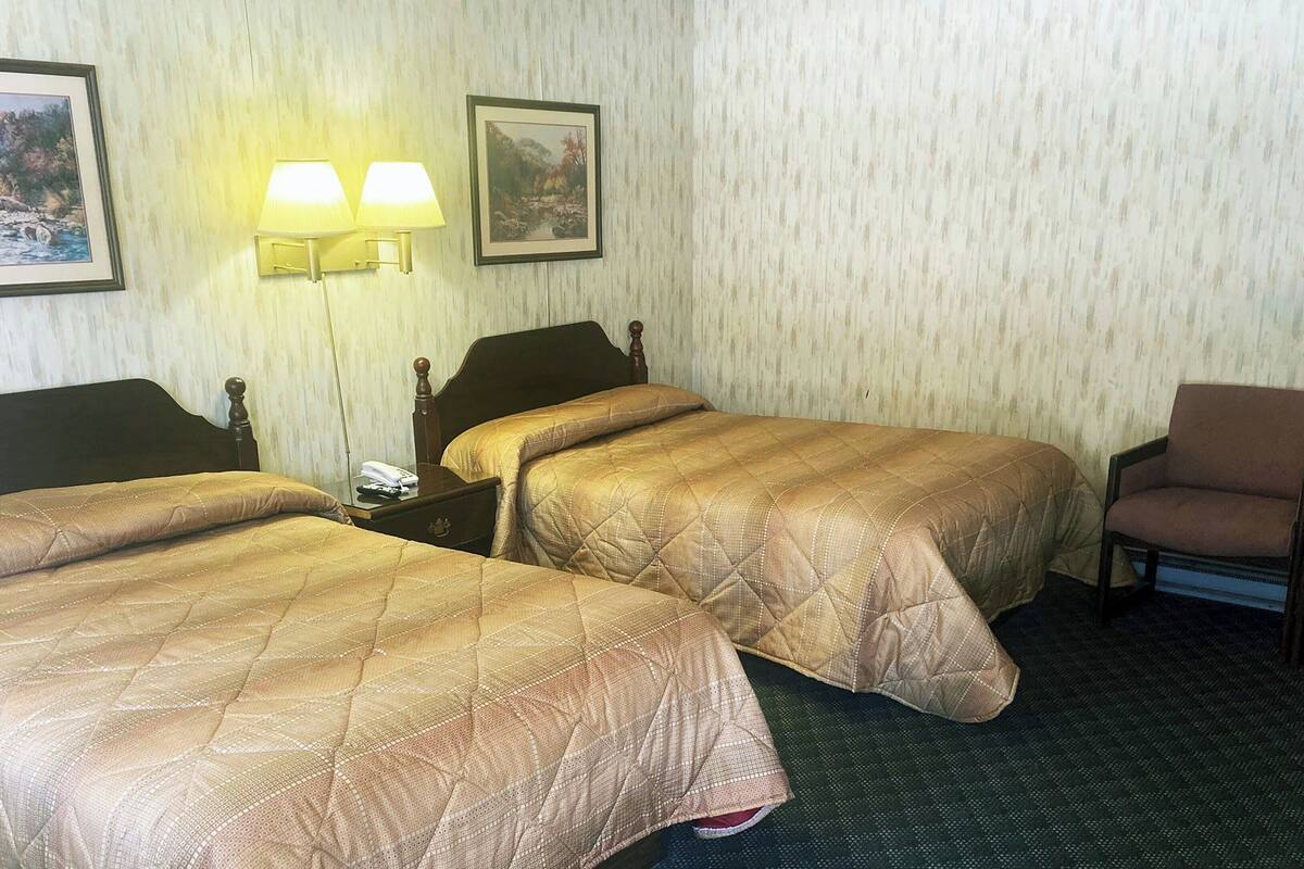 Ein Hotelzimmer mit zwei Betten, einem Sessel und zwei Wandleuchten.