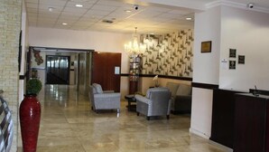 A hotel lobby with a reception desk, seating area, and a chandelier.