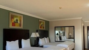 A hotel room with two beds, a large mirror, and artwork on the walls.