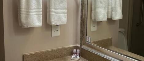A bathroom with a sink, mirror, and two towels hanging on a towel rack.