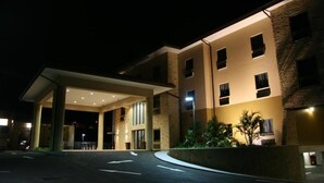 A hotel entrance with a covered driveway, a stone facade, and a landscaped area with plants.