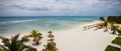 Rannalla, valkoista hiekkaa, aurinkotuoleja, aurinkovarjoja