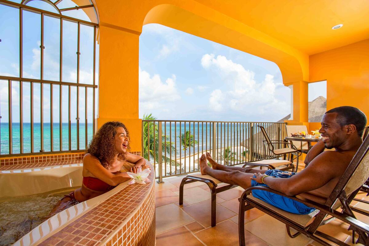 A couple relaxing on a balcony with a view of the ocean.