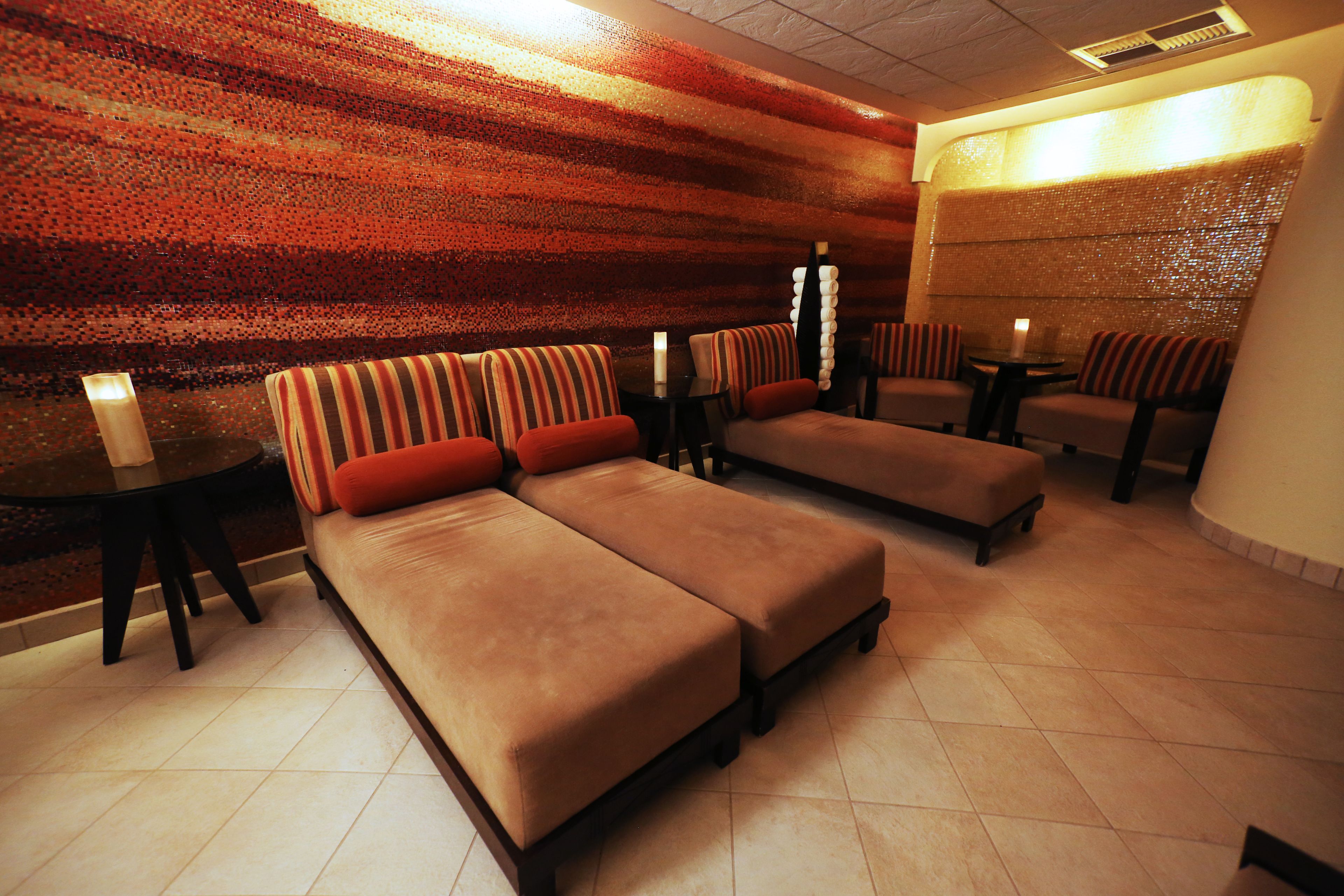A spa room with two sofas and two small tables, each with a candle.
