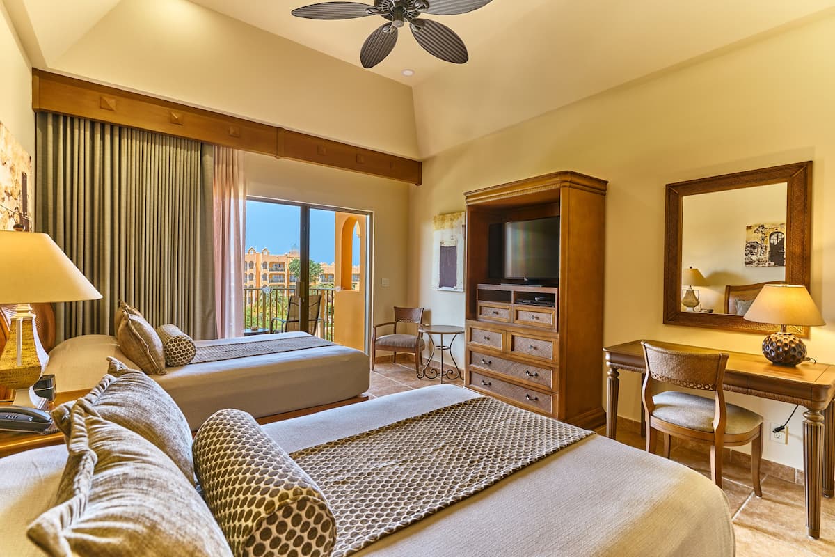 A hotel room with a bed, a desk, a chair, a television, and a large window with curtains.