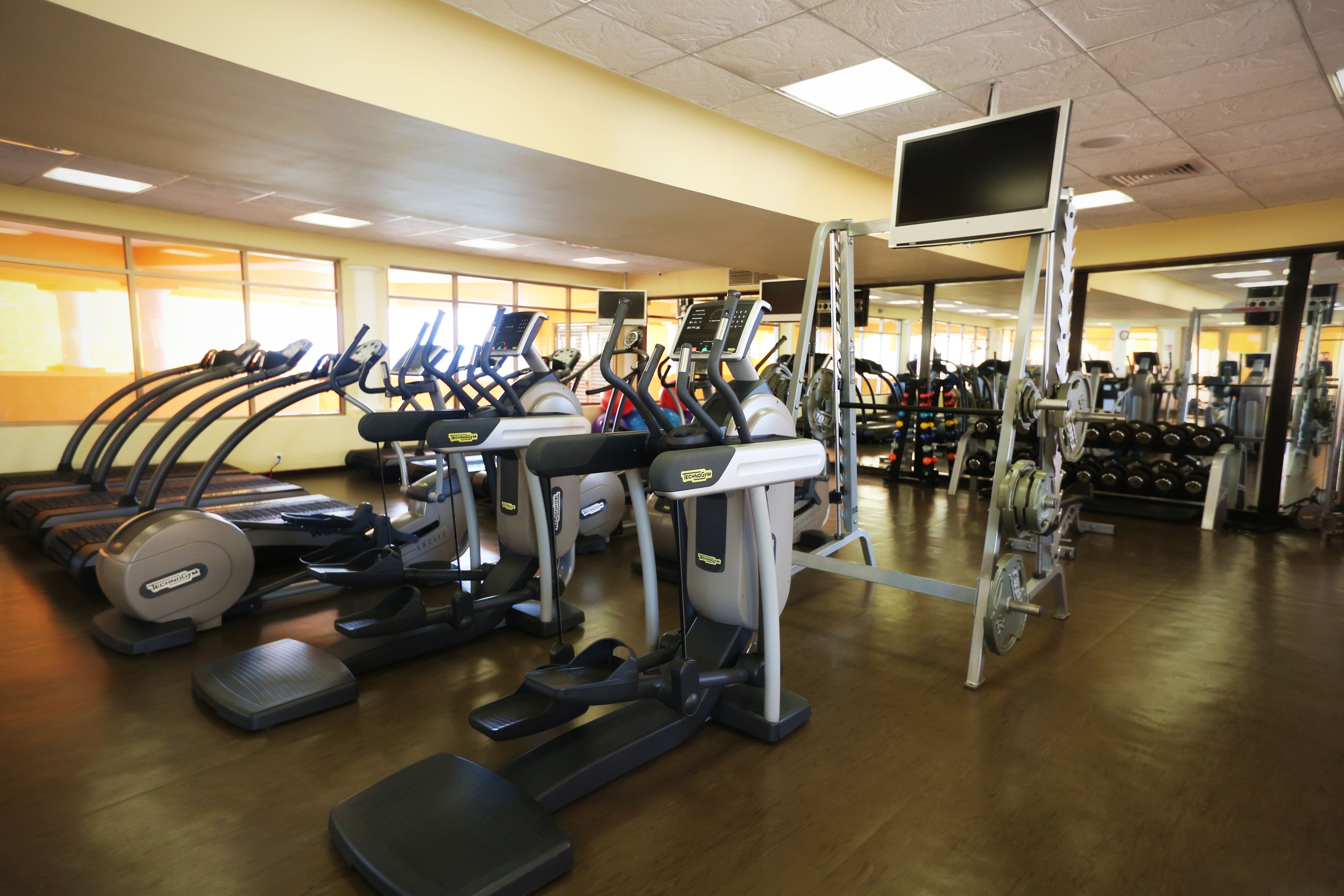 A gym with treadmills, elliptical machines, and weight equipment.
