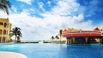 Relax by the oceanfront pool surrounded by palm trees and a historic building with a unique facade.