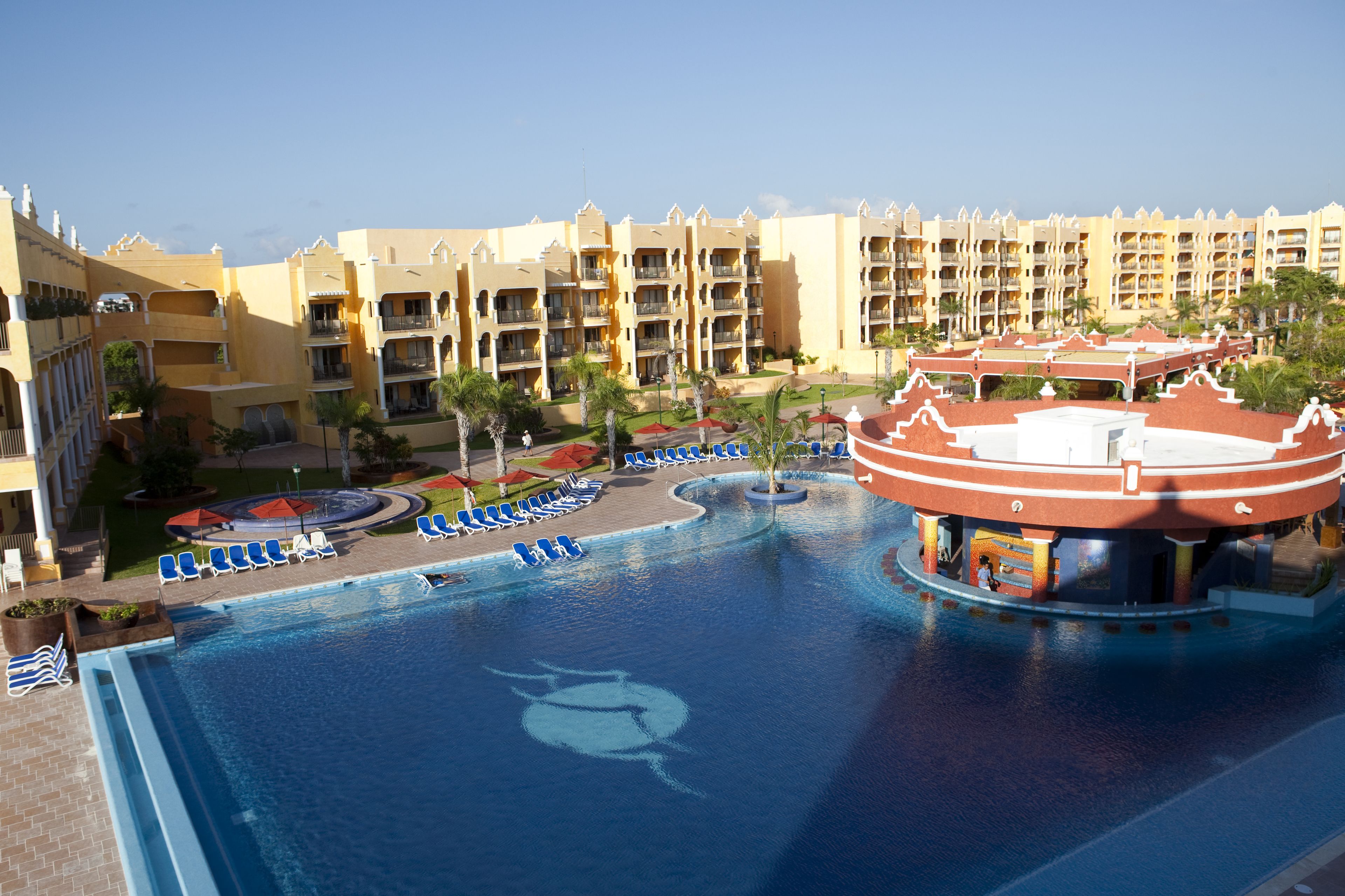 Un resort con una gran piscina, varios balcones y una fuente central.