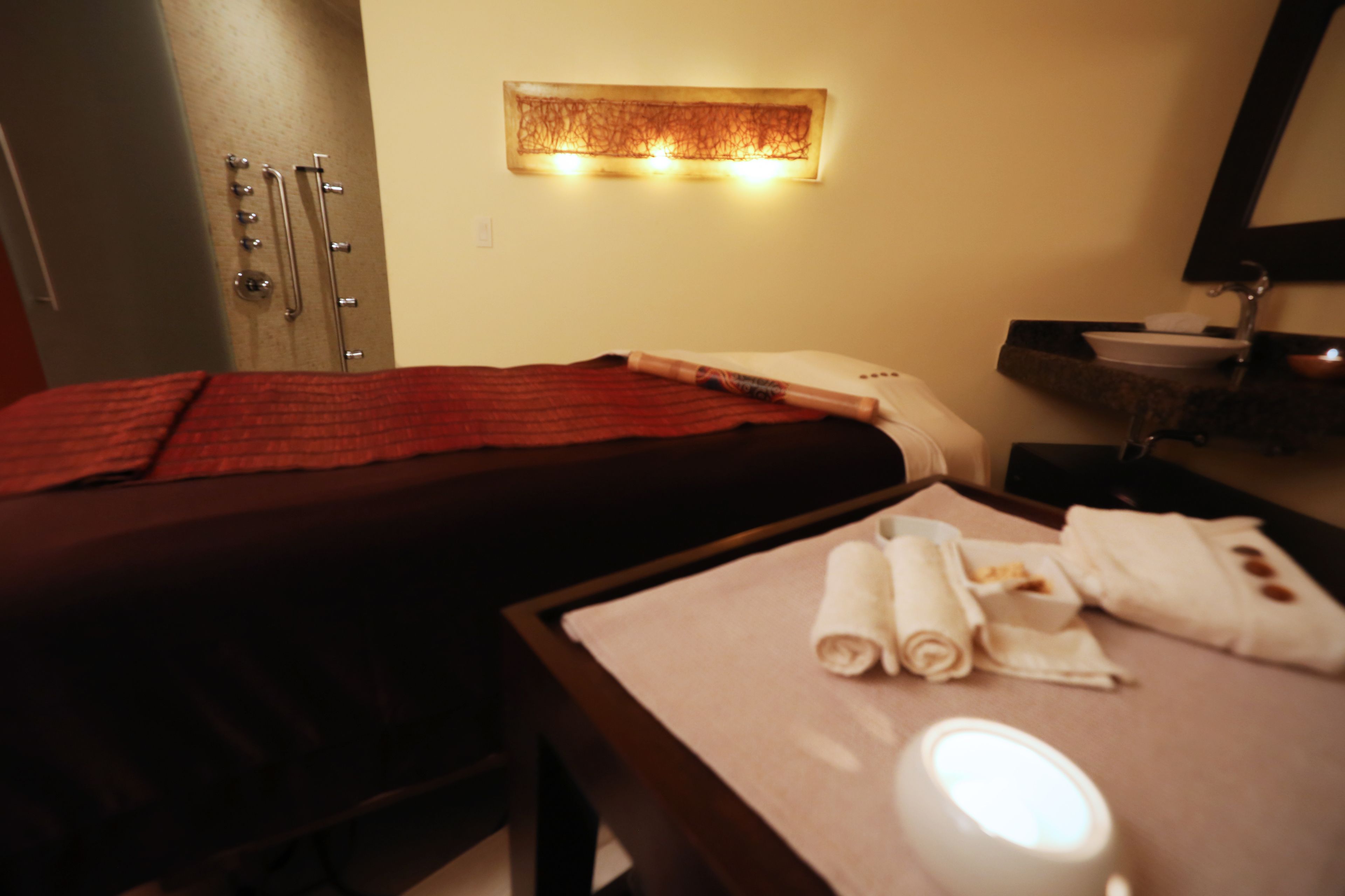 Une chambre d’hôtel équipée d’un lit, d’une table de massage, d’un lavabo et d’un miroir.