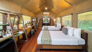 Una habitación con carpa, una cama grande, un escritorio con una silla y una escalera.