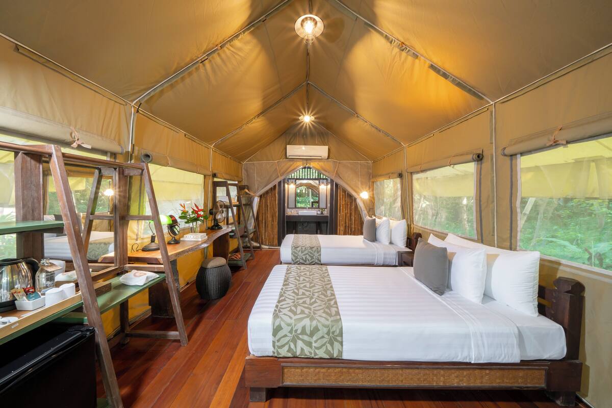 Una habitación con carpa, una cama grande, un escritorio con una silla y una escalera.