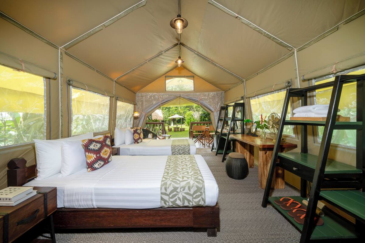 Alojamiento con carpa que incluye dos camas, una zona de comedor y vistas al exterior.