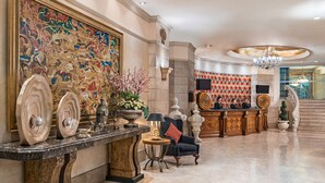 A lobby with a marble floor, a reception desk, a large abstract painting, and a chandelier. - Makati Palace Hotel (Makati)