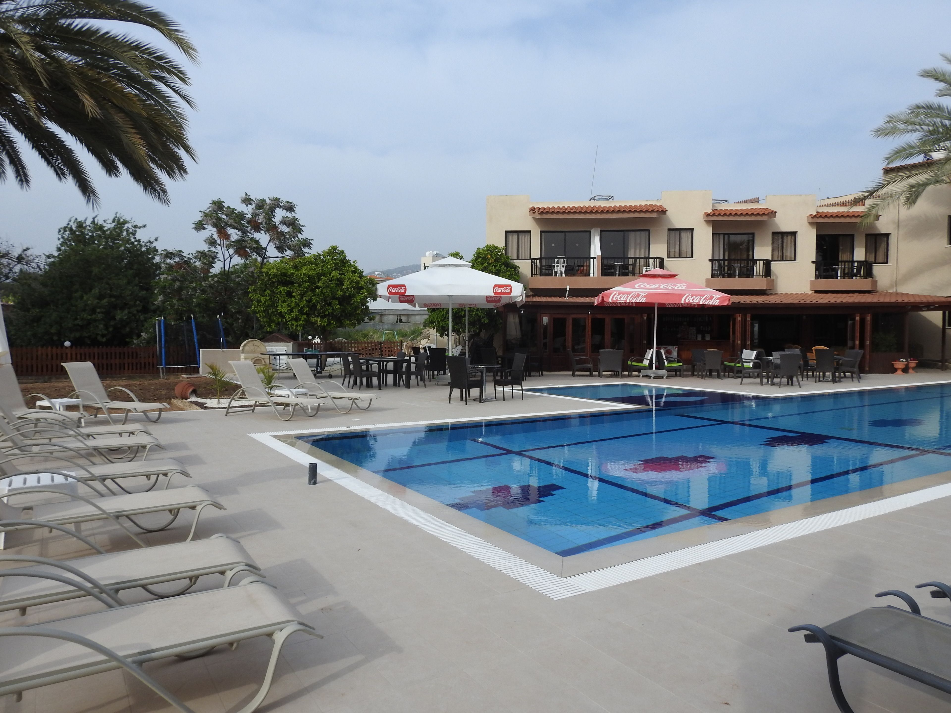 A swimming pool with lounge chairs and umbrellas, surrounded by buildings with balconies.