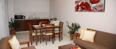 A modern living room with a brown sofa, a wooden dining table with chairs, and a kitchen in the background.