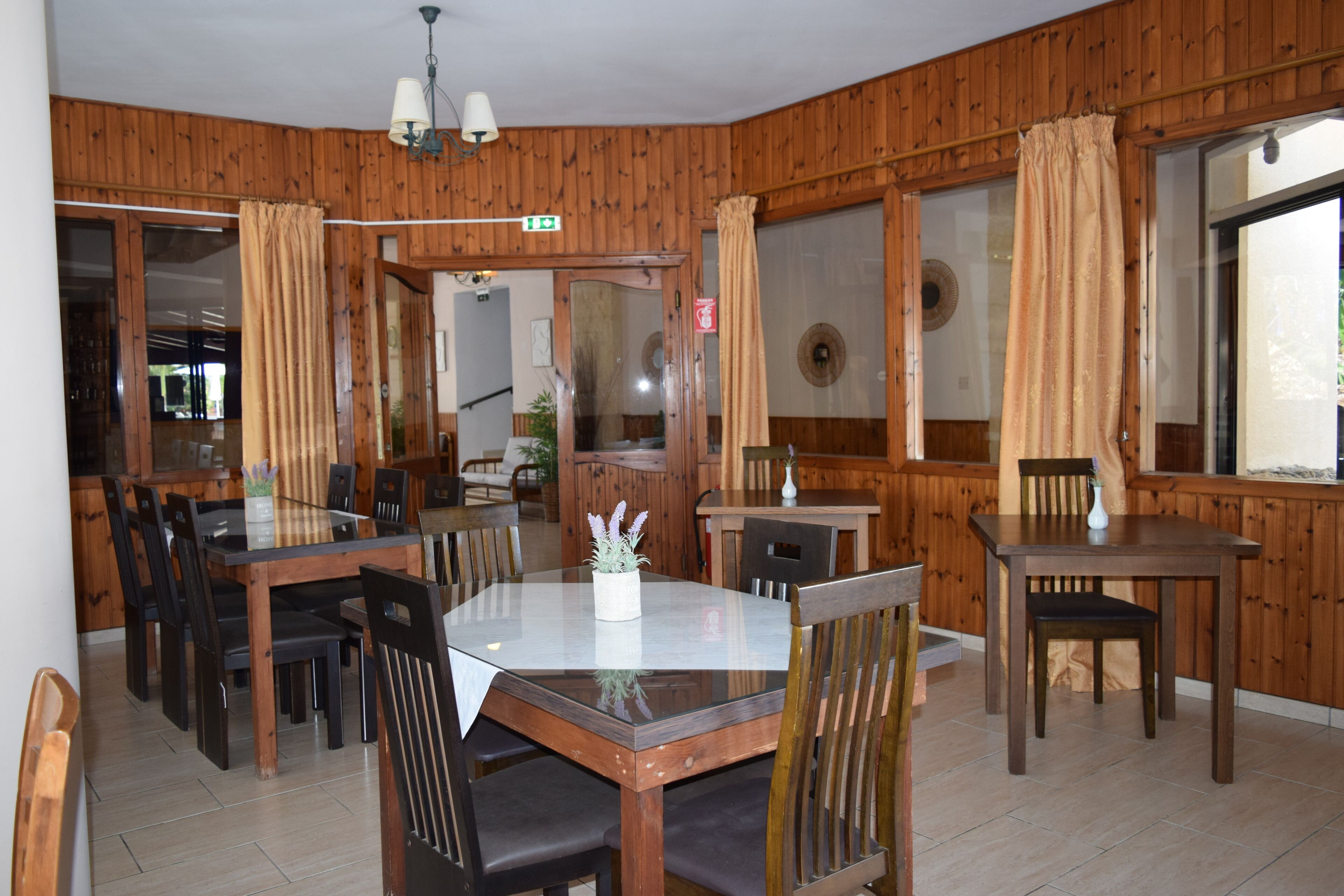 A dining area with wooden paneling, a glass table, and multiple chairs.