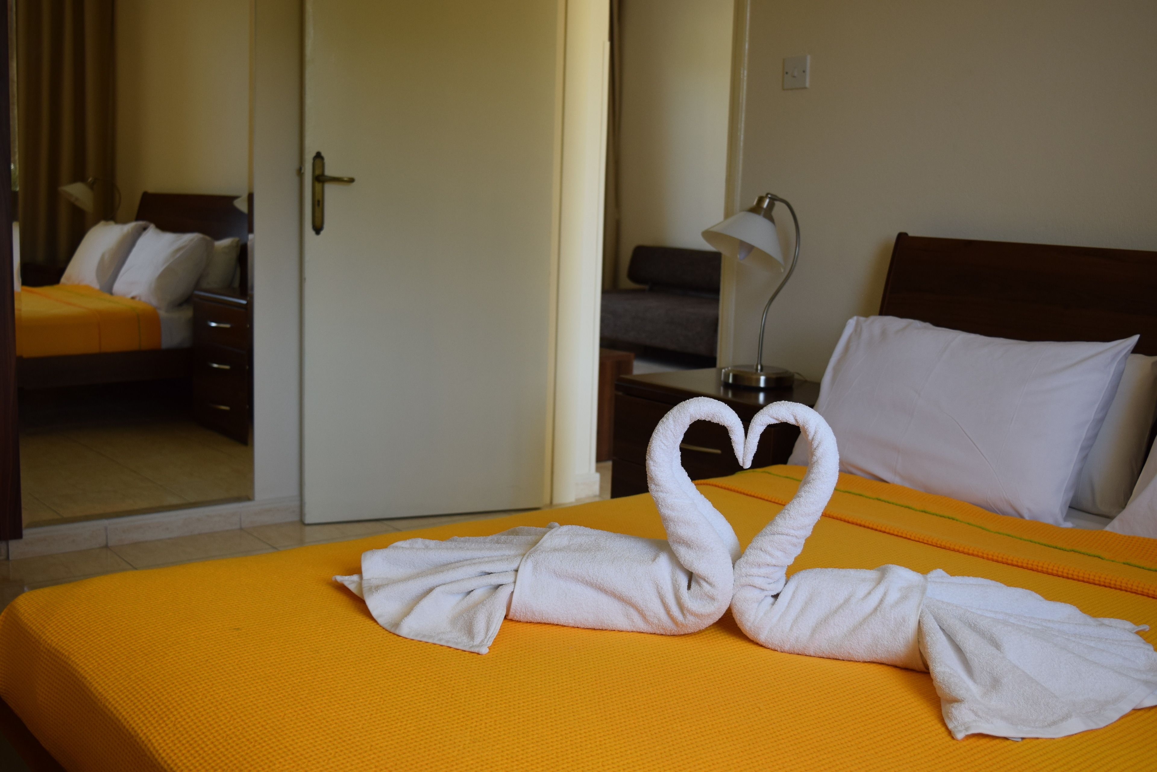 A hotel room with a bed, a nightstand, and a lamp.
