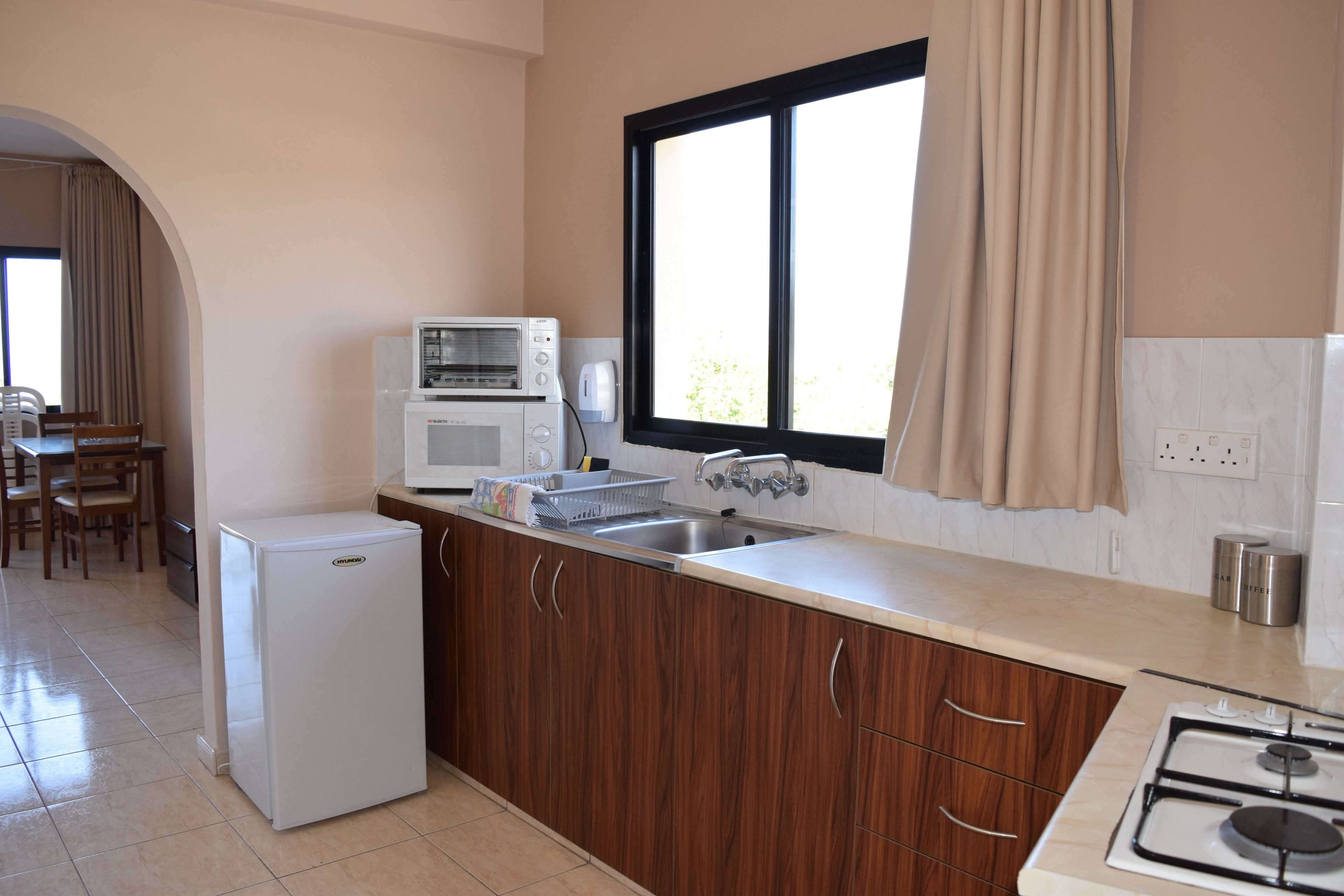 A compact kitchen with a refrigerator, microwave, sink, and stove.