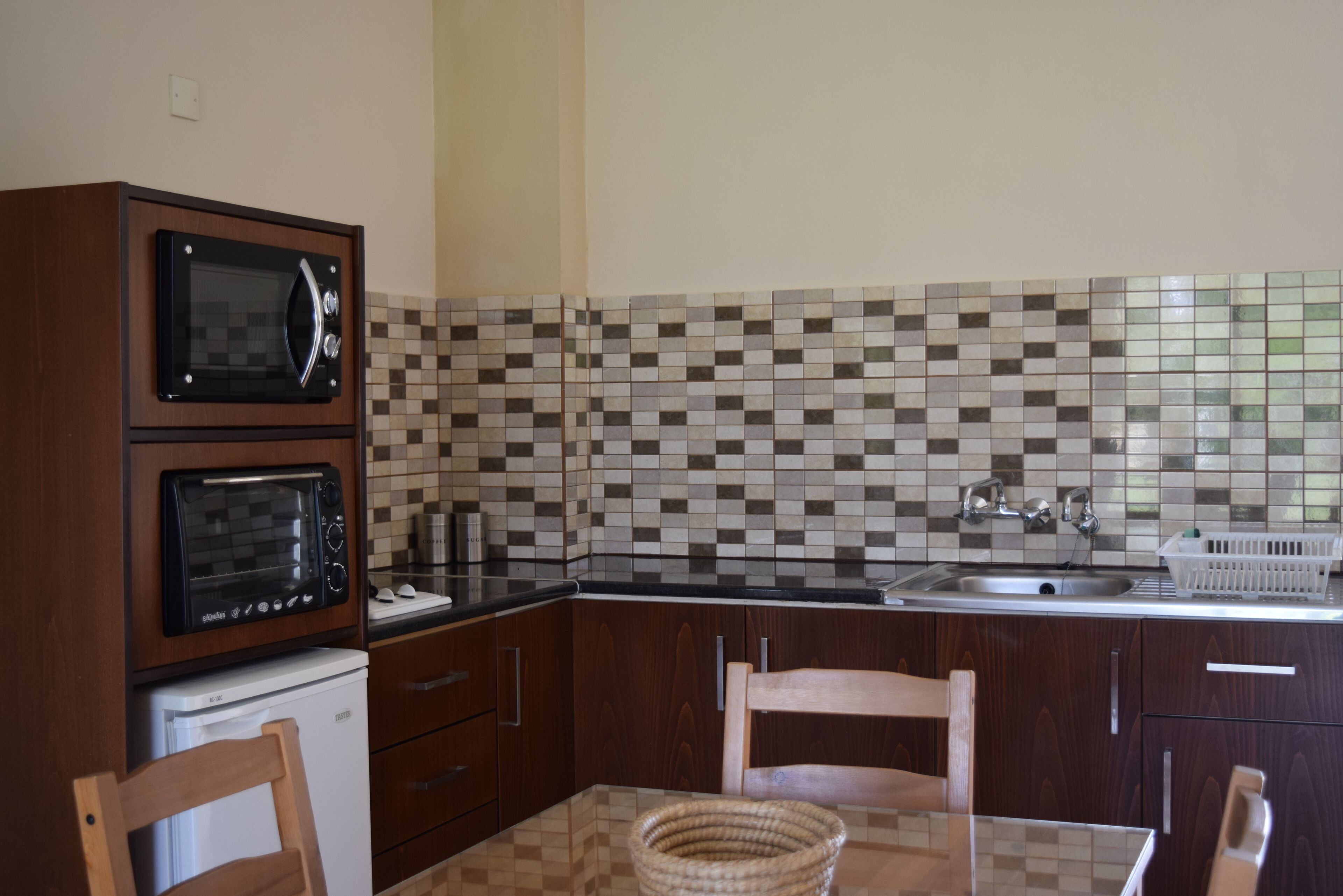 A kitchen with two wall-mounted ovens, a sink, and a tiled backsplash.