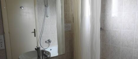 Un baño con lavamanos, espejo, ducha y bañera.
