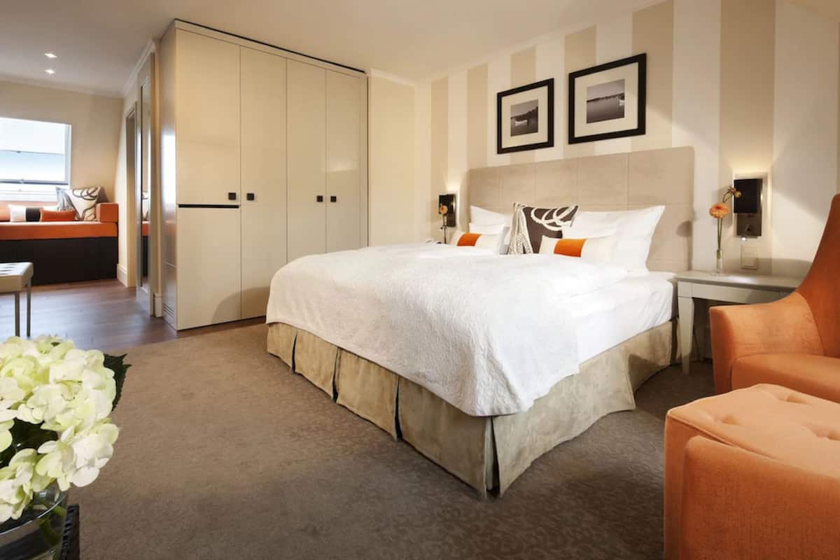 Habitación de hotel moderna con una cama grande, un escritorio y una silla. Cuenta con un armario y una ventana con vistas.