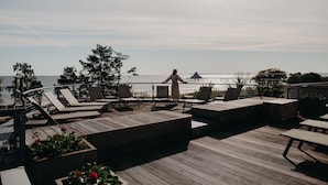 A wooden deck with lounge chairs and a view of the sea. - Strandhotel Ostseeblick (Heringsdorf)