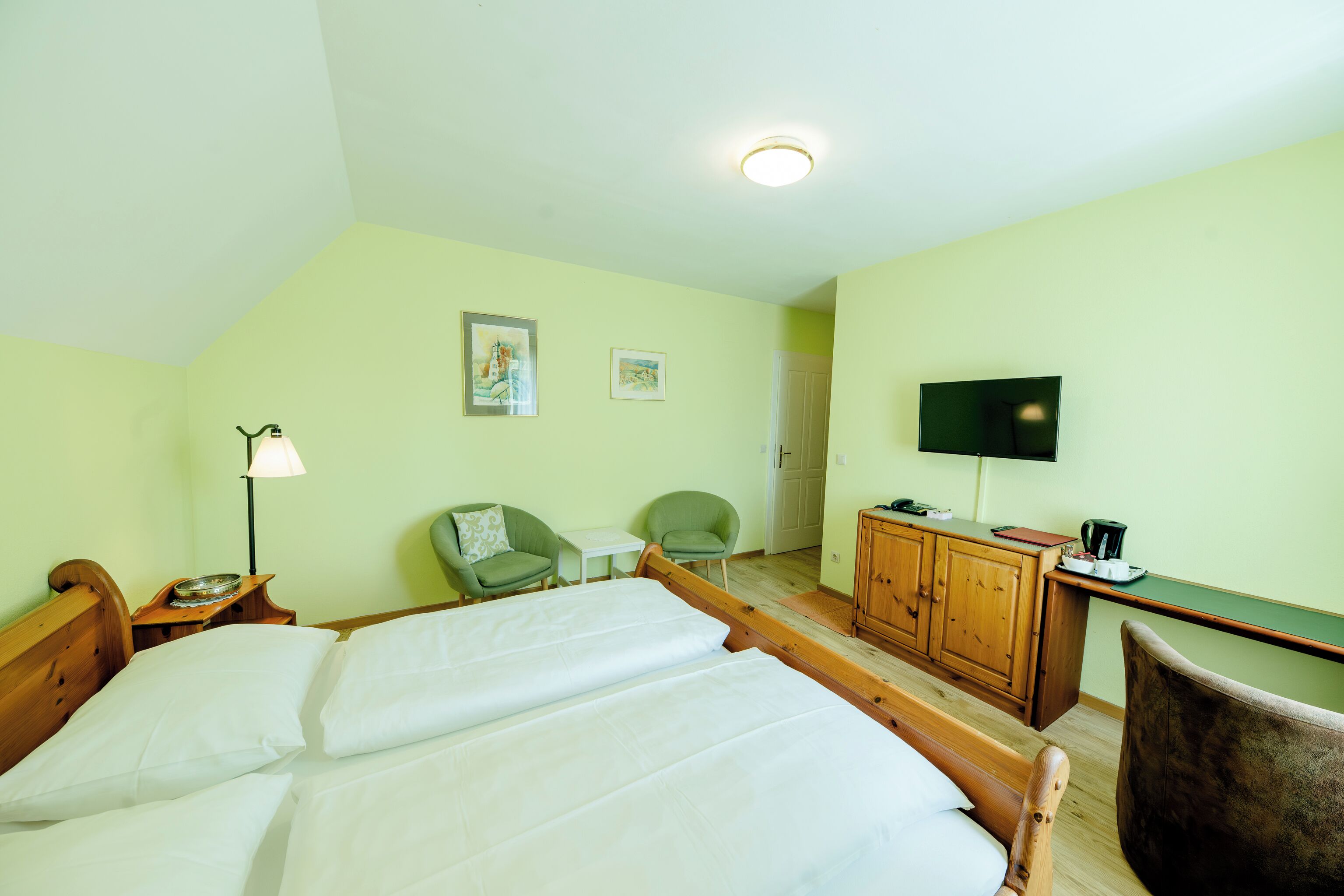 Una habitación de hotel con dos camas, un escritorio, un televisor y dos sillas.