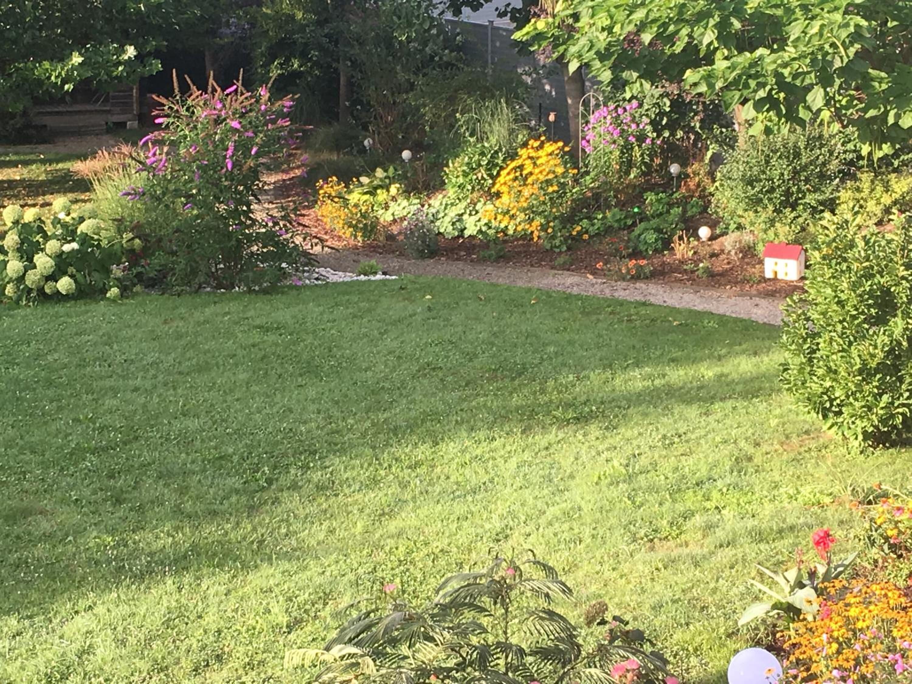 Un jardin bien entretenu, agrémenté de diverses plantes à fleurs et d’une pelouse parfaitement taillée.