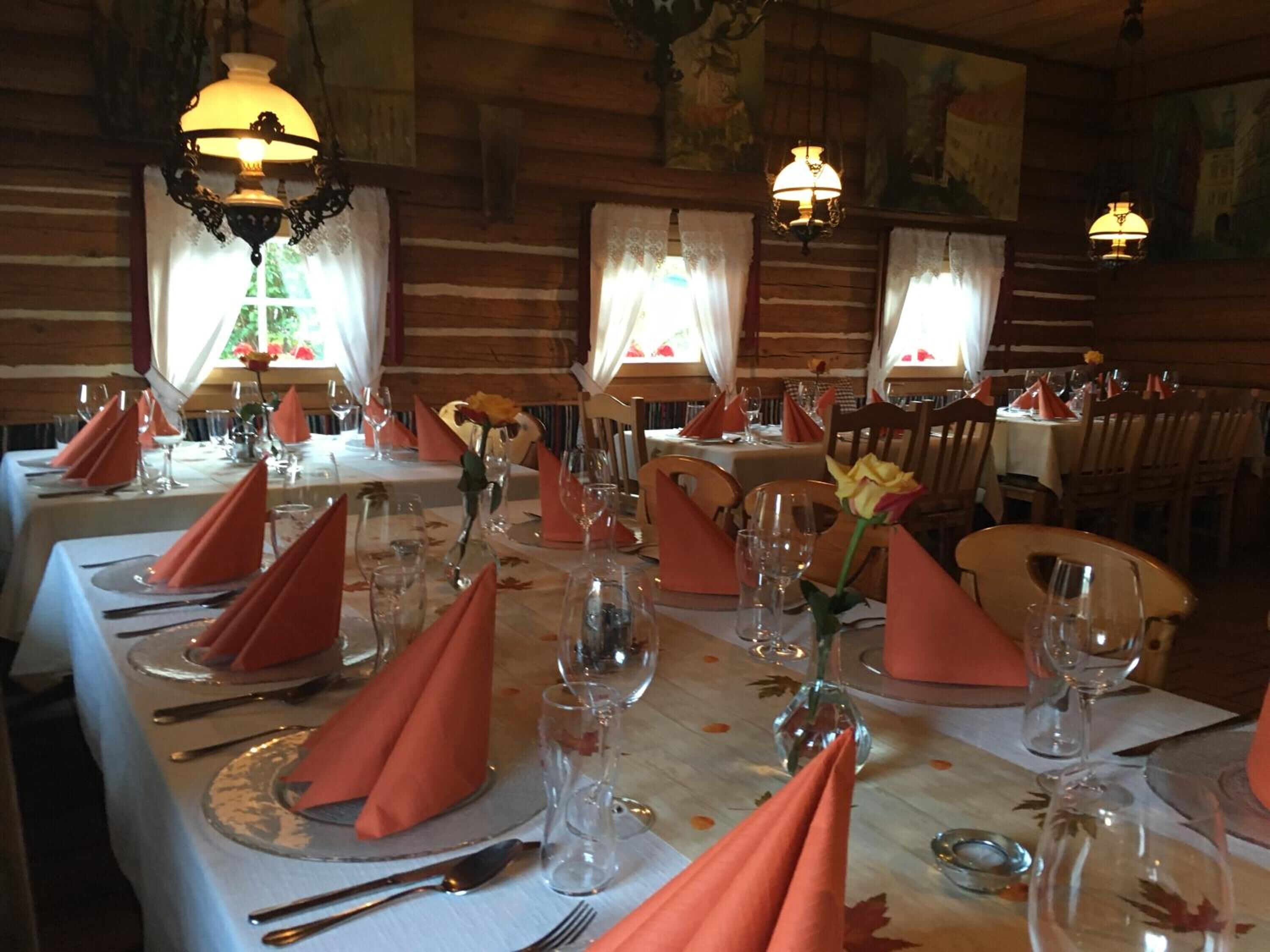 Ein Restaurant mit gedeckten Tischen, das ein rustikales Holzinnere und warme Beleuchtung bietet.