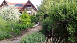 Ein Haus mit rotem Dach, umgeben von üppigem Grün und einem Kiesweg.