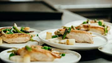 Une table à manger avec des assiettes remplies de nourriture, notamment du poulet grillé et des légumes.